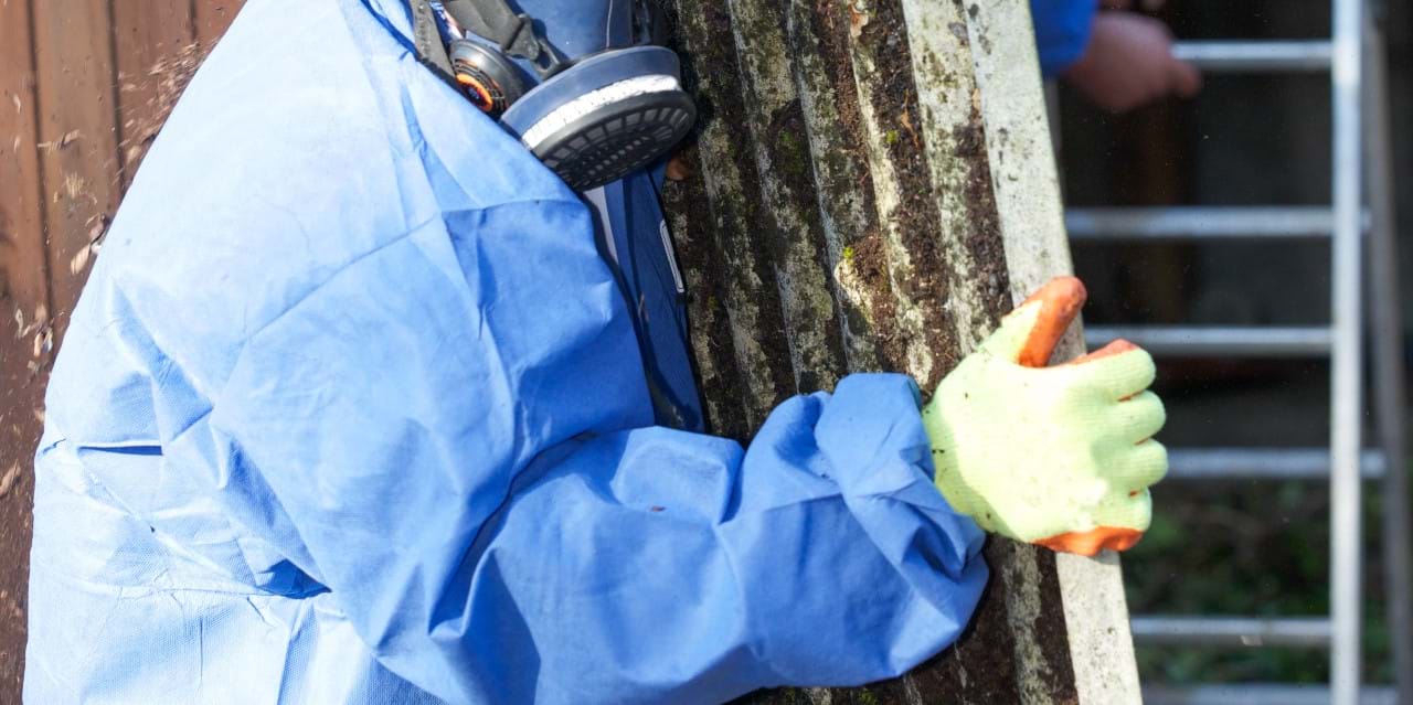 Worker wearing PPE removes asbestos